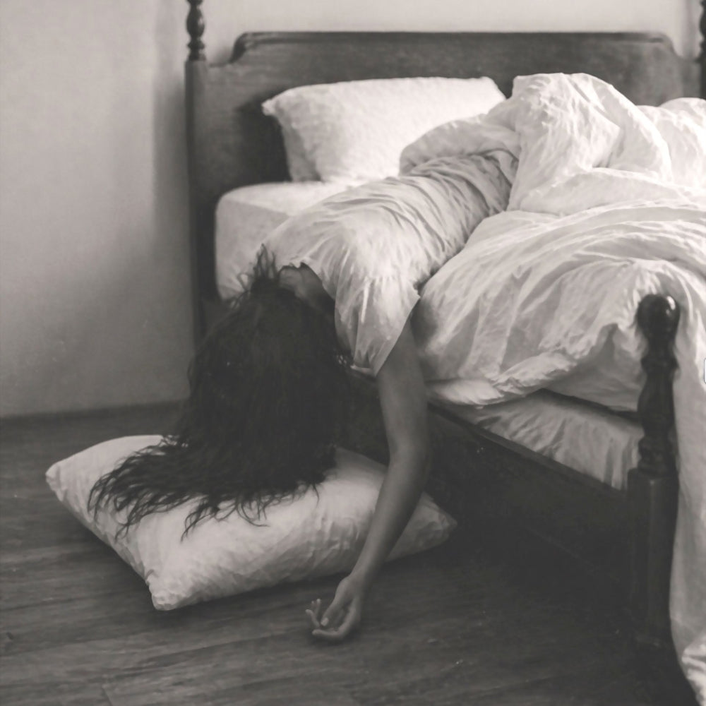 Exhausted woman lying across her bed after disrupted sleep during perimenopause.